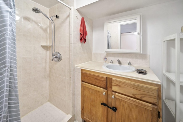 bathroom with a tile shower and vanity
