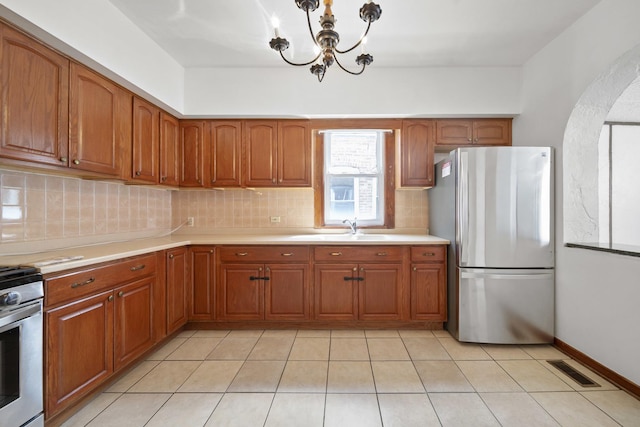 kitchen featuring appliances with stainless steel finishes, a sink, brown cabinetry, and backsplash
