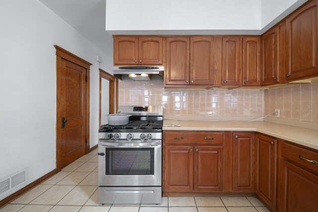 kitchen with stainless steel range with gas stovetop, ventilation hood, backsplash, and light countertops
