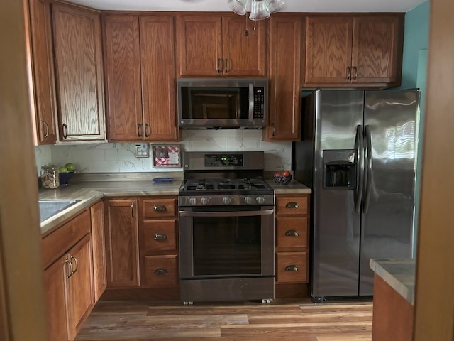 5116 154th St, Oak Forest, IL 60452 - kitchen featuring stainless steel appliances, tasteful backsplash, brown cabinets, wood finished floors, and a sink