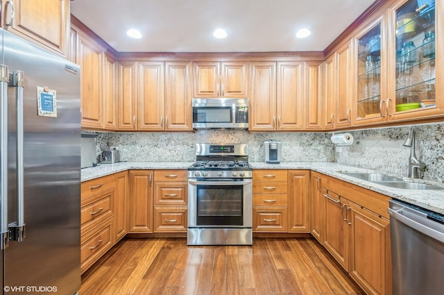 5639 W Montrose Ave, Chicago, IL 60634 - kitchen with stainless steel appliances, a sink, wood finished floors, light stone countertops, and tasteful backsplash