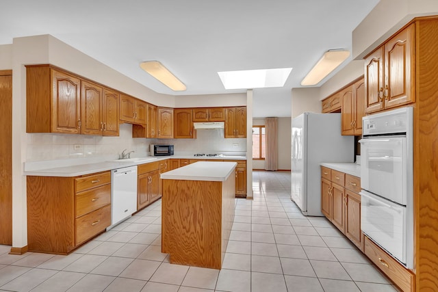 1212 Ashford Ln, Joliet, IL 60431 - kitchen featuring white appliances, a skylight, light countertops, a kitchen island, and a sink