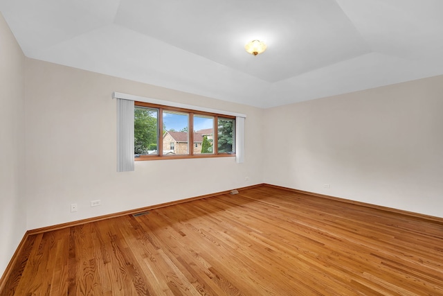1212 Ashford Ln, Joliet, IL 60431 - spare room featuring light wood-style floors, vaulted ceiling, a raised ceiling, and baseboards