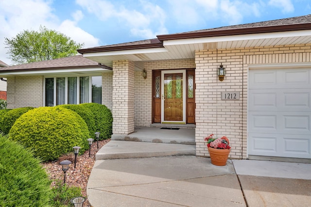 1212 Ashford Ln, Joliet, IL 60431 - property entrance with brick siding, a garage, driveway, and a shingled roof