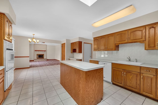 1212 Ashford Ln, Joliet, IL 60431 - kitchen with white appliances, a sink, a chandelier, a brick fireplace, and light countertops