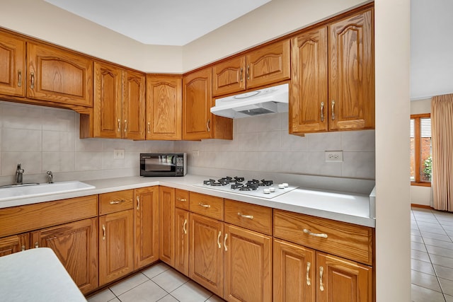 1212 Ashford Ln, Joliet, IL 60431 - kitchen featuring under cabinet range hood, white gas cooktop, light tile patterned flooring, a sink, and brown cabinetry