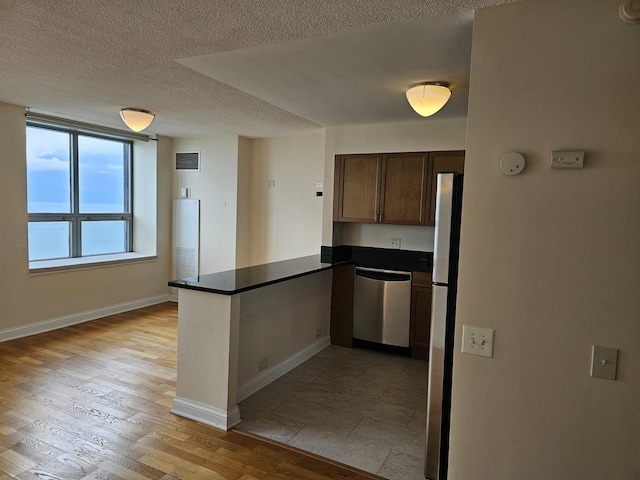 474 N Lake Shore Dr Unit 5306, Chicago, IL 60611 - kitchen with stainless steel appliances, a peninsula, dark countertops, light wood finished floors, and a textured ceiling