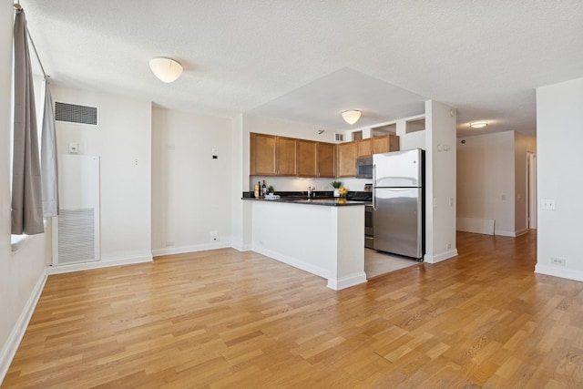 474 N Lake Shore Dr Unit 5306, Chicago, IL 60611 - kitchen featuring stainless steel appliances, dark countertops, light wood-type flooring, a peninsula, and brown cabinets