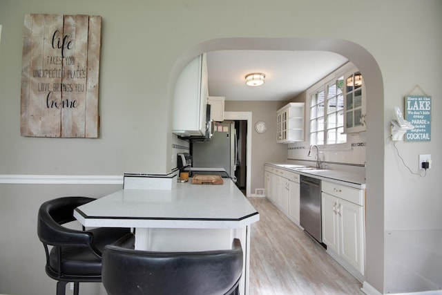 39270 N Lake Ave, Lake Villa, IL 60046 - kitchen featuring stainless steel dishwasher, a sink, glass insert cabinets, white cabinetry, and arched walkways