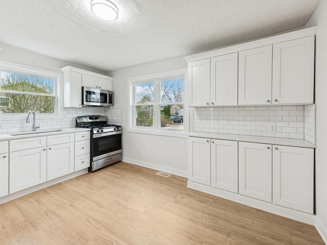 520 W Pheasant Ct, Round Lake Beach, IL 60073 - kitchen featuring appliances with stainless steel finishes, a sink, light countertops, light wood-style flooring, and backsplash