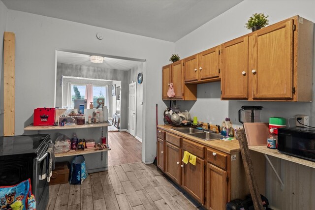 3823 W Wabansia Ave, Chicago, IL 60647 - kitchen with black microwave, a sink, light wood-style flooring, light countertops, and brown cabinets