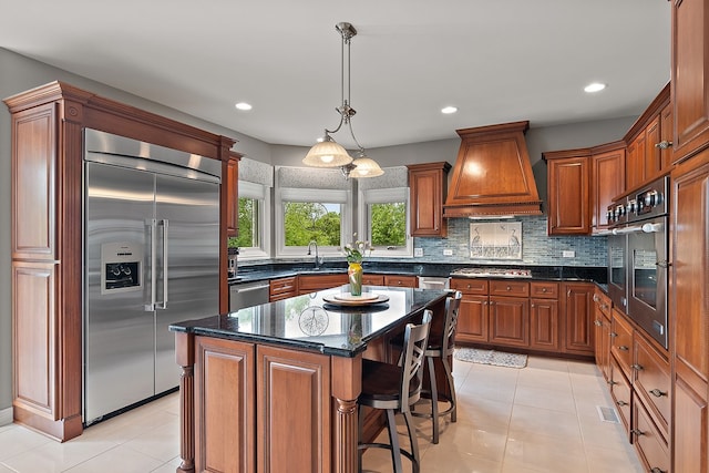 21186 Sage Brush Ln, Mokena, IL 60448 - kitchen with appliances with stainless steel finishes, custom range hood, a kitchen breakfast bar, light tile patterned floors, and a center island