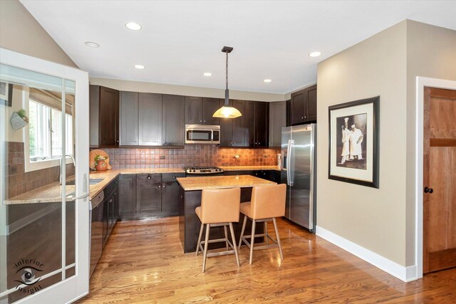 1233 Prairie Ln, Lemont, IL 60439 - kitchen with stainless steel appliances, a kitchen island, a breakfast bar area, light stone counters, and light wood finished floors