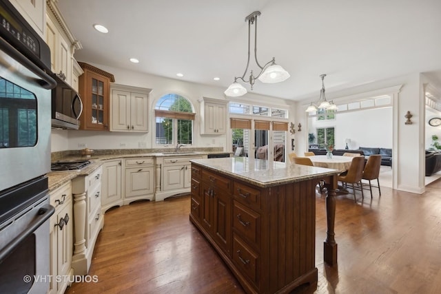 3620 Schillinger Ct, Naperville, IL 60564 - kitchen featuring cream cabinetry, appliances with stainless steel finishes, glass insert cabinets, a sink, and a kitchen breakfast bar