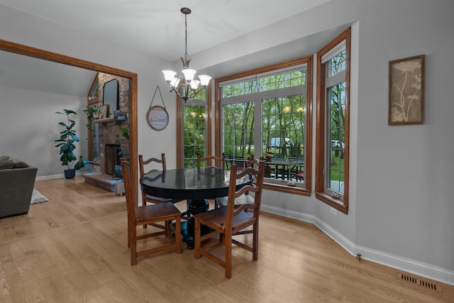 10920 Preservation Way, Richmond, IL 60071 - dining space featuring baseboards, a chandelier, light wood-style floors, and a fireplace