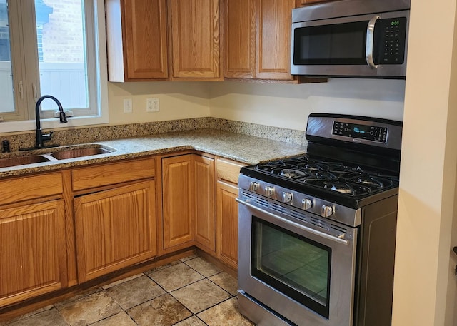 526 Marquette Ave, Calumet City, IL 60409 - kitchen featuring appliances with stainless steel finishes, a sink, brown cabinetry, and light stone counters