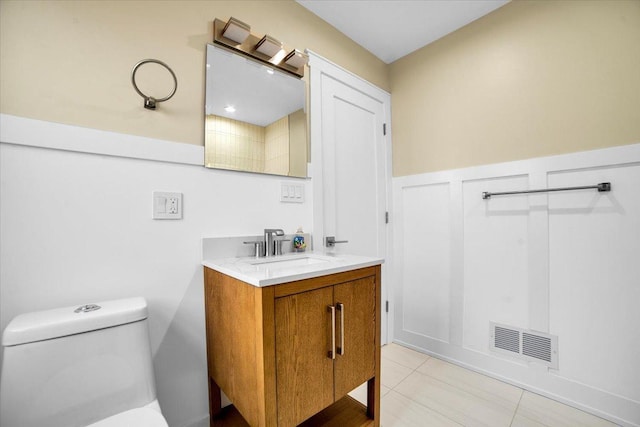 6014 W Fletcher St, Chicago, IL 60634 - bathroom featuring vanity, toilet, tile patterned flooring, and a wainscoted wall