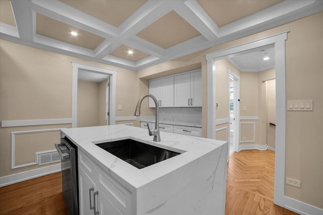 6014 W Fletcher St, Chicago, IL 60634 - kitchen featuring a sink, white cabinetry, a wainscoted wall, light stone counters, and a center island with sink