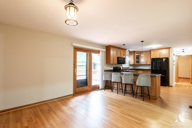 14940 Wilco Dr, Homer Glen, IL 60491 - kitchen featuring black appliances, light wood-type flooring, a breakfast bar, and a peninsula