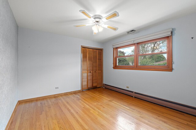 9017 S 50th Ave, Oak Lawn, IL 60453 - unfurnished bedroom with a baseboard heating unit, a closet, light wood-style floors, baseboards, and a ceiling fan