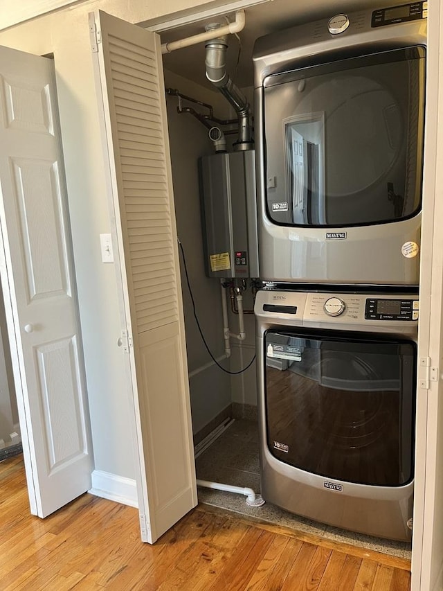 501 W 60th Pl Unit 3, Chicago, IL 60621 - laundry room featuring stacked washer and clothes dryer, light wood-style floors, tankless water heater, and baseboards