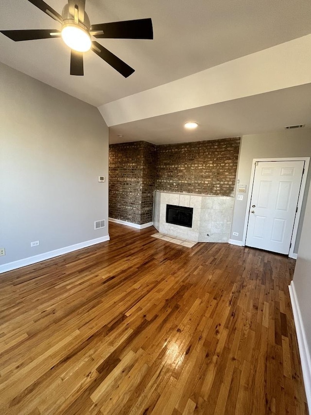 501 W 60th Pl Unit 3, Chicago, IL 60621 - unfurnished living room featuring baseboards, dark wood-style floors, brick wall, a tile fireplace, and a ceiling fan
