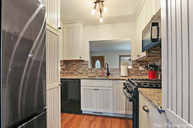 1428 Juneway Ter, Round Lake Beach, IL 60073 - kitchen featuring black appliances, decorative backsplash, a sink, light wood finished floors, and light stone countertops