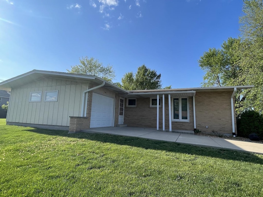 240 S Rathje Rd, Peotone, IL 60468 - rear view of house with an attached garage, brick siding, and a lawn