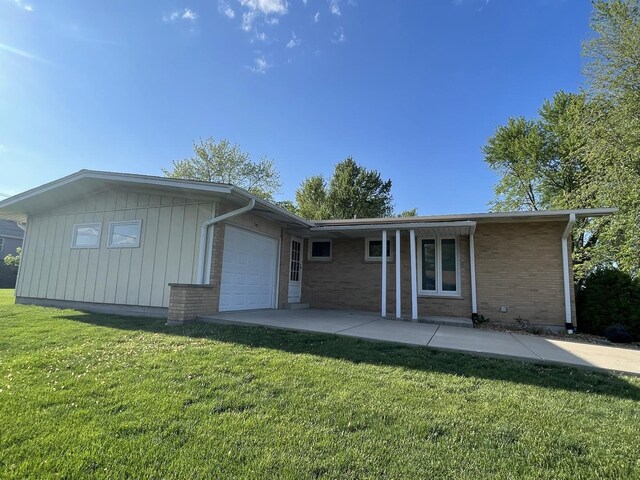 240 S Rathje Rd, Peotone, IL 60468 - rear view of house with an attached garage, brick siding, and a lawn