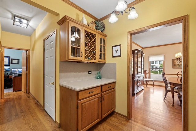 730 N Hundley St, Hoffman Estates, IL 60169 - bar area with light wood finished floors, crown molding, a chandelier, and baseboards