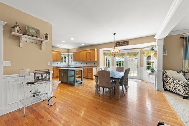 10423 Capistrano Ln, Orland Park, IL 60467 - dining space with light wood-style flooring, a wainscoted wall, a chandelier, recessed lighting, and ornate columns