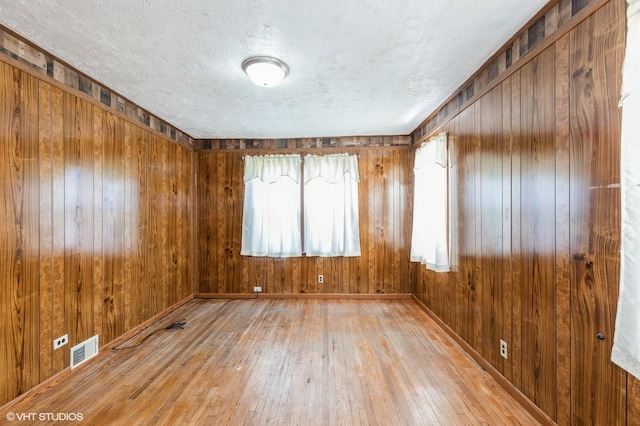 10624 S Ave H Rd, Chicago, IL 60617 - spare room with hardwood / wood-style floors, wooden walls, and a textured ceiling