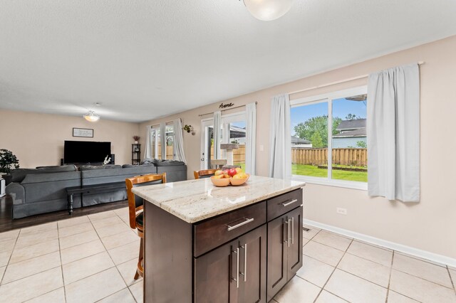5401 W Arlington Dr, Hanover Park, IL 60133 - kitchen featuring light tile patterned flooring, dark brown cabinets, light stone countertops, and baseboards