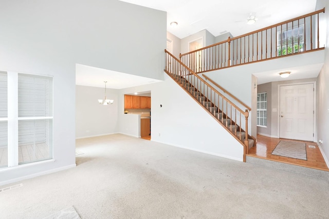 876 Dandridge Ct, Elgin, IL 60120 - unfurnished living room with a high ceiling, carpet, stairway, baseboards, and a chandelier