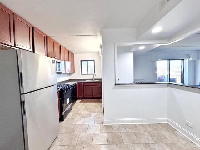 735 N Swift Rd Unit 102, Addison, IL 60101 - kitchen with freestanding refrigerator, black gas range oven, a sink, baseboards, and white microwave