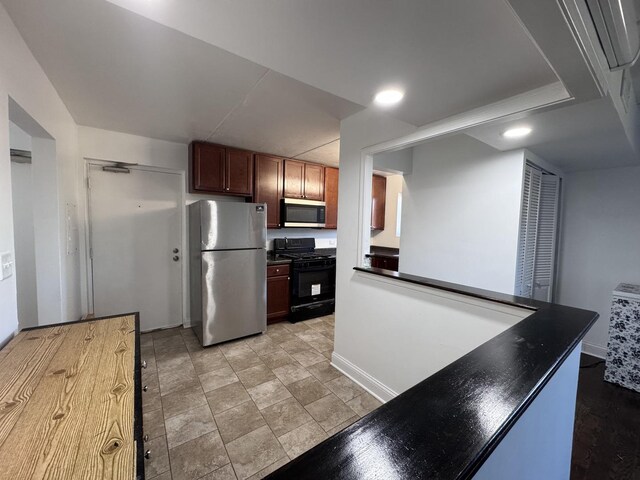 735 N Swift Rd Unit 102, Addison, IL 60101 - kitchen featuring freestanding refrigerator, black gas range oven, stainless steel microwave, dark countertops, and baseboards