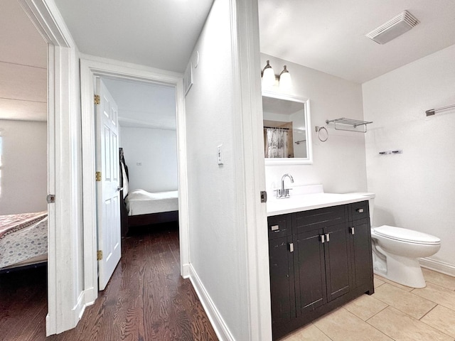 735 N Swift Rd Unit 102, Addison, IL 60101 - full bath featuring toilet, vanity, wood finished floors, baseboards, and connected bathroom