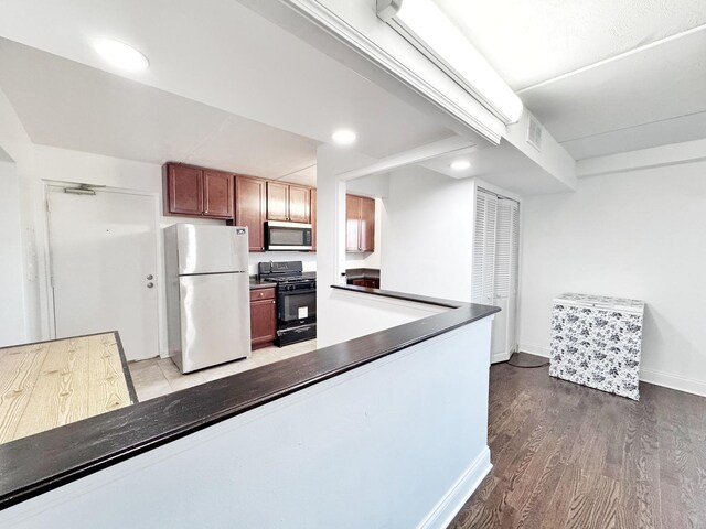 735 N Swift Rd Unit 102, Addison, IL 60101 - kitchen with freestanding refrigerator, black gas range oven, stainless steel microwave, dark countertops, and wood finished floors