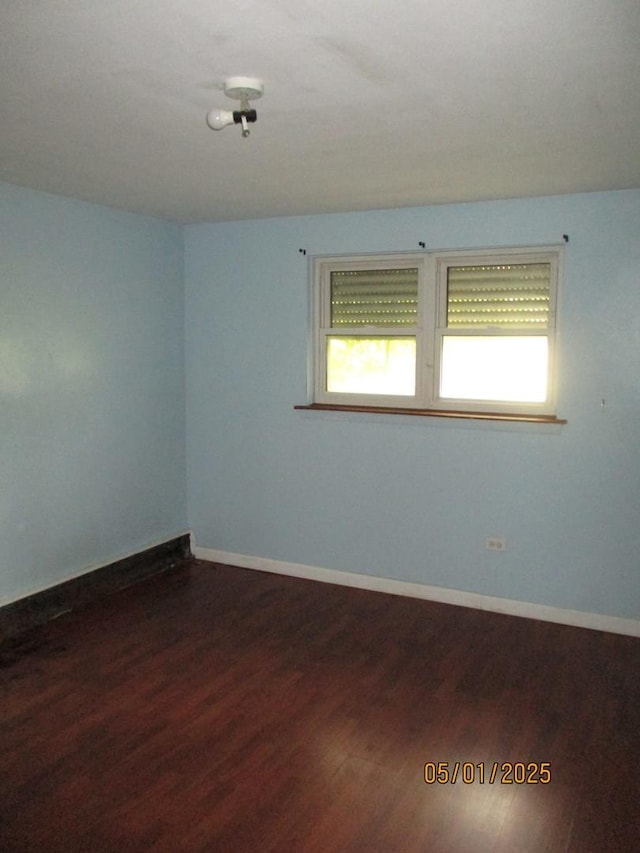 unfurnished room featuring dark wood-type flooring and baseboards