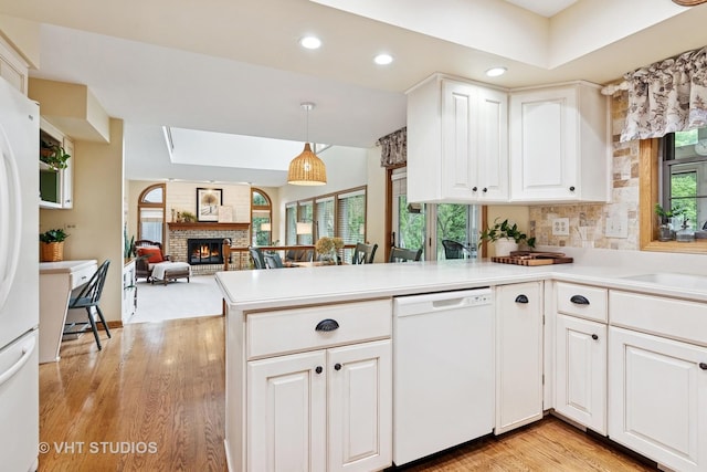 1965 Jamestown Ln, Elgin, IL 60123 - kitchen featuring white appliances, a fireplace, a peninsula, light wood-type flooring, and light countertops