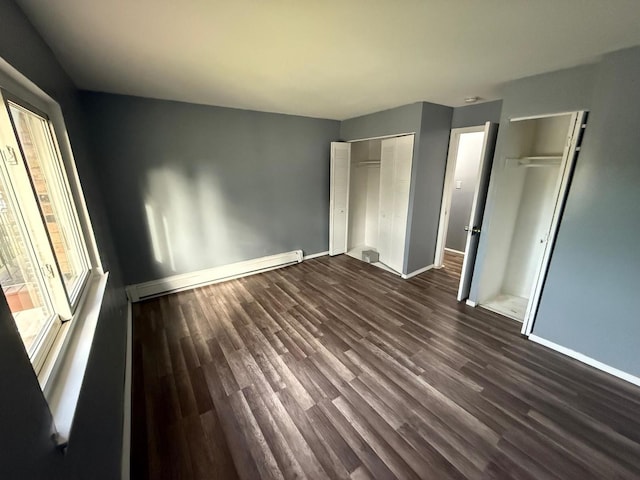 605 Hill Dr Unit 206, Hoffman Estates, IL 60169 - unfurnished bedroom with baseboards, dark wood-type flooring, baseboard heating, and two closets