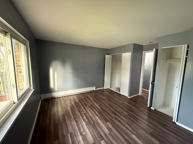 605 Hill Dr Unit 206, Hoffman Estates, IL 60169 - unfurnished bedroom with baseboard heating, baseboards, dark wood finished floors, and multiple closets