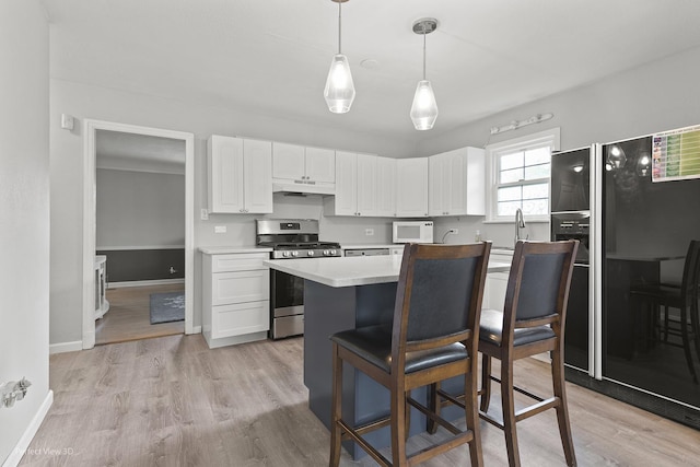 990 Magnolia Ave, Gurnee, IL 60031 - kitchen featuring stainless steel gas range oven, white microwave, under cabinet range hood, freestanding refrigerator, and white cabinets