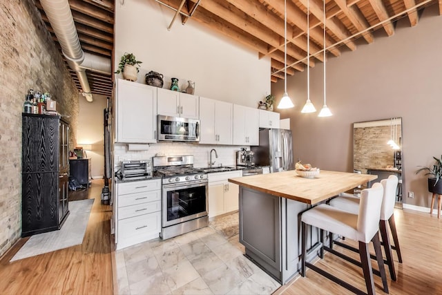 525 N Halsted St Unit 409, Chicago, IL 60642 - kitchen featuring appliances with stainless steel finishes, wood counters, a sink, a high ceiling, and a breakfast bar area