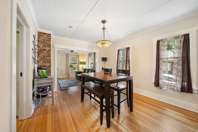 dining room featuring crown molding, light wood-style floors, and baseboards