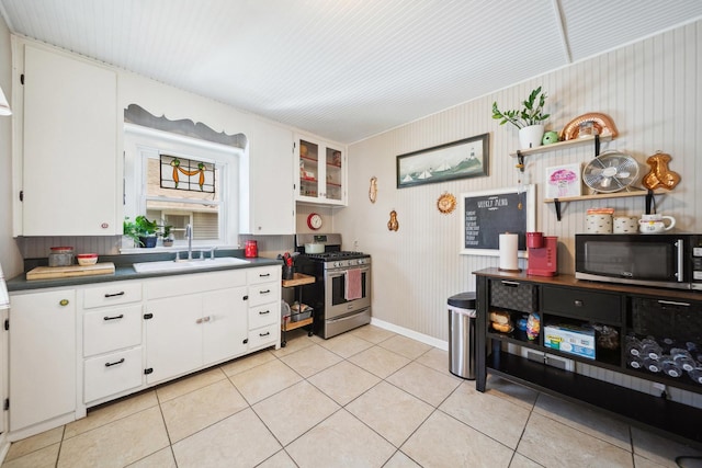 kitchen with appliances with stainless steel finishes, a sink, dark countertops, and white cabinets