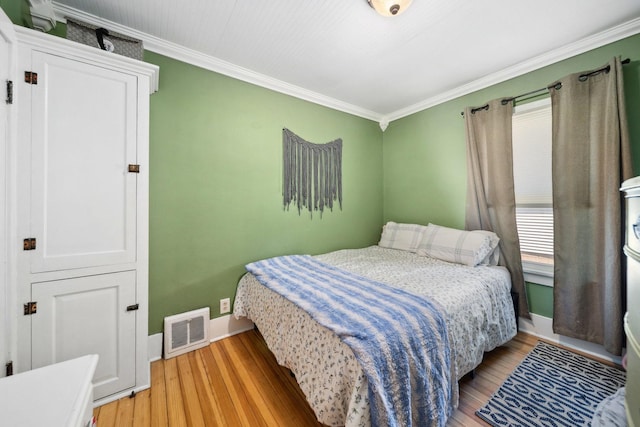 bedroom featuring baseboards, light wood finished floors, and crown molding