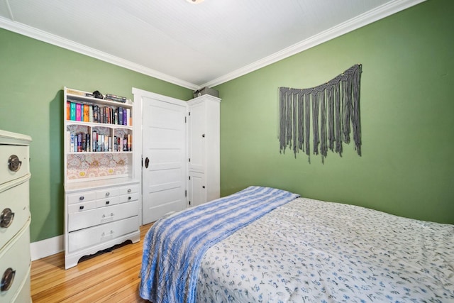 bedroom featuring crown molding and light wood finished floors