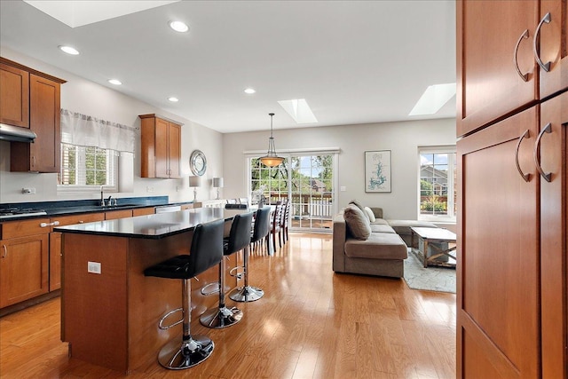 13093 Timber Ct Unit 61, Palos Heights, IL 60463 - kitchen with a skylight, light wood-style floors, a kitchen bar, brown cabinetry, and recessed lighting
