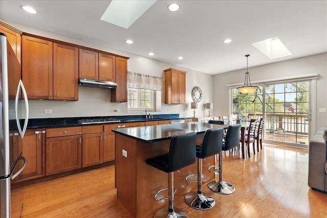 13093 Timber Ct Unit 61, Palos Heights, IL 60463 - kitchen featuring a skylight, under cabinet range hood, brown cabinetry, freestanding refrigerator, and light wood-type flooring